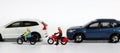 Miniature motorcycle messenger between miniature cars. Royalty Free Stock Photo