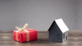 Miniature paper model of the house. Gift in a red package with a banot. Concept of mortgage, rent, purchase, protection, construct Royalty Free Stock Photo