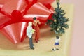 Miniature Parents celebrating christmas with their little boy on top of a gift box