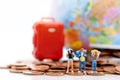 Miniature people, backpackers standing on stack of coins