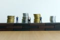 Miniature people - barrier to entry business concept. Group of businessman standing above brick wall make a barricade