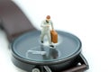 Miniature people : business man looking at watch and walk on the