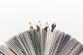 Miniature people, Business team sitting on book, reading news paper,using as background business, education concept