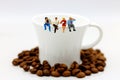 Miniature people: business team sitting on cup of coffee with morning news. Coffee time of business concept