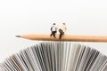 Miniature people, Business team sitting on pencil, reading news paper,using as background business, education concept. Royalty Free Stock Photo
