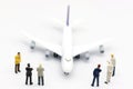 Miniature people: Business team standing in front of airplane. B Royalty Free Stock Photo