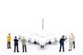 Miniature people: Business team standing in front of airplane. B Royalty Free Stock Photo