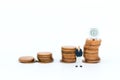 Miniature people: Businessman looking for stack of coins. Image use for background money growth up, saving, financial, business