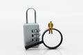 Miniature people: Businessman with a magnifying glass and master key encoding. Image use for background security system