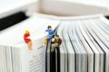 Miniature people: Businessman reading newspaper and sitting on b Royalty Free Stock Photo