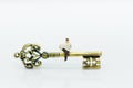 Miniature people: Businessman sitting on key and reading newspaper. Image use for key man, the key to success, business concept