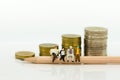 Miniature people: Businessman sitting on pencil and reading newspaper, stack of coins of background. Image use for business concep Royalty Free Stock Photo