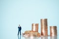 Miniature people: Businessman stack of coins with copy space