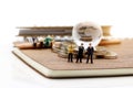 Miniature people: Businessman standing on book with step of coin Royalty Free Stock Photo