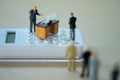 Miniature people businessman standing on calculator and talk to staff Royalty Free Stock Photo