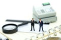 Miniature people: businessman standing on calculator using as ba Royalty Free Stock Photo