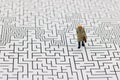 Miniature people: Businessman standing on center of maze. Concepts of finding a solution, problem solving and challenge. Royalty Free Stock Photo