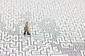 Miniature people: Businessman standing on center of maze. Concepts of finding a solution, problem solving and challenge. Royalty Free Stock Photo