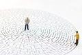 Miniature people: Businessman standing on center of maze. Royalty Free Stock Photo