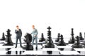 Miniature people Businessman standing on chessboard