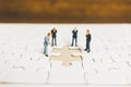 Miniature people: Businessman standing on jigsaw