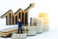 Miniature people : Businessman standing on stack of coin and wooden chart. Image use for benefit, business vision Concept