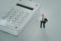 Miniature people: businessman standing on the white calculator. Financial and business concept Royalty Free Stock Photo