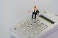 Miniature people: businessman standing on the white calculator. Financial and business concept Royalty Free Stock Photo