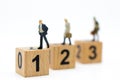Miniature people : Businessman standing on wooden blocks with sequential numbers. Image use for business concept
