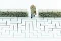 Miniature people: Businessman walking to wall in maze. Concepts of finding a solution, problem solving and challenge Royalty Free Stock Photo