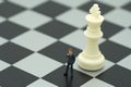 Miniature people businessmen standing on a chessboard with a che Royalty Free Stock Photo