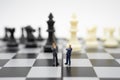 Miniature people businessmen standing on a chessboard with a chess piece on the back Negotiating in business. as background Royalty Free Stock Photo