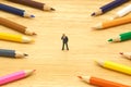 Miniature people businessmen standing Colorful wooden pencils surround a circle on a wood background. Make a center Can be used Royalty Free Stock Photo