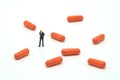Miniature people businessmen standing and orange capsule medicine. on white background using as background business concept and H