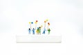 Miniature people, children holding colorful balloon on white box. White block can write anything for various occasions Royalty Free Stock Photo