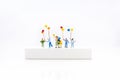 Miniature people, children holding colorful balloon on white box. White block can write anything for various occasions