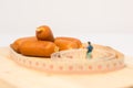 Miniature people : Close up fat man standing in waist tape measure and looking at sausages Royalty Free Stock Photo