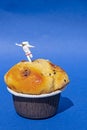 Miniature People concept, close up miniature astronaut standing on muffin, over blue background.