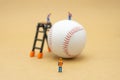 Miniature people Construction worker with baseball on Abstract background and red stitching baseball. White baseball with red Royalty Free Stock Photo