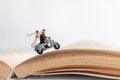 Miniature people : Couple riding the motorcycle on old book