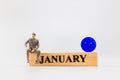 Miniature people, A dejected businessman is sitting on a wooden with Blue face emoji , Blue monday concept