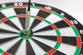 Miniature people digging the arrow in the middle of the target to the dart board. Concept of doing for goals Royalty Free Stock Photo