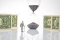 Miniature people. an elderly pensioner man stands near dollar money, an hourglass. concept of time and provision of old age Royalty Free Stock Photo