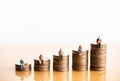 Miniature people: Elderly people sitting on coins stack.