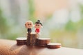 Miniature people, elderly people sitting on stack coins Royalty Free Stock Photo