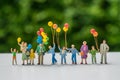 Miniature people with family holding balloon with green color ba