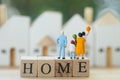 Miniature people: Family stand on wood block words HOME and looking to home