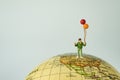 Miniature people figure happy kid / boy holding balloons standing on united states of america map on globe as world climate chang Royalty Free Stock Photo