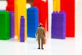 Miniature people. figures of people stand near the colored blocks of a plastic constructor on a white background in the form of Royalty Free Stock Photo