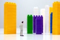 Miniature people. figures of people stand near the colored blocks of a plastic constructor on a white background in the form of Royalty Free Stock Photo